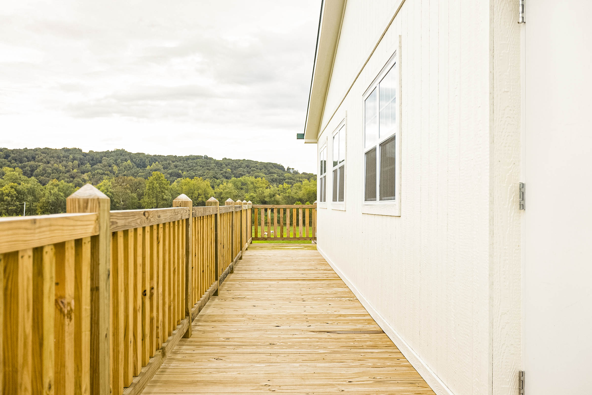 a deck with a fence and a white building