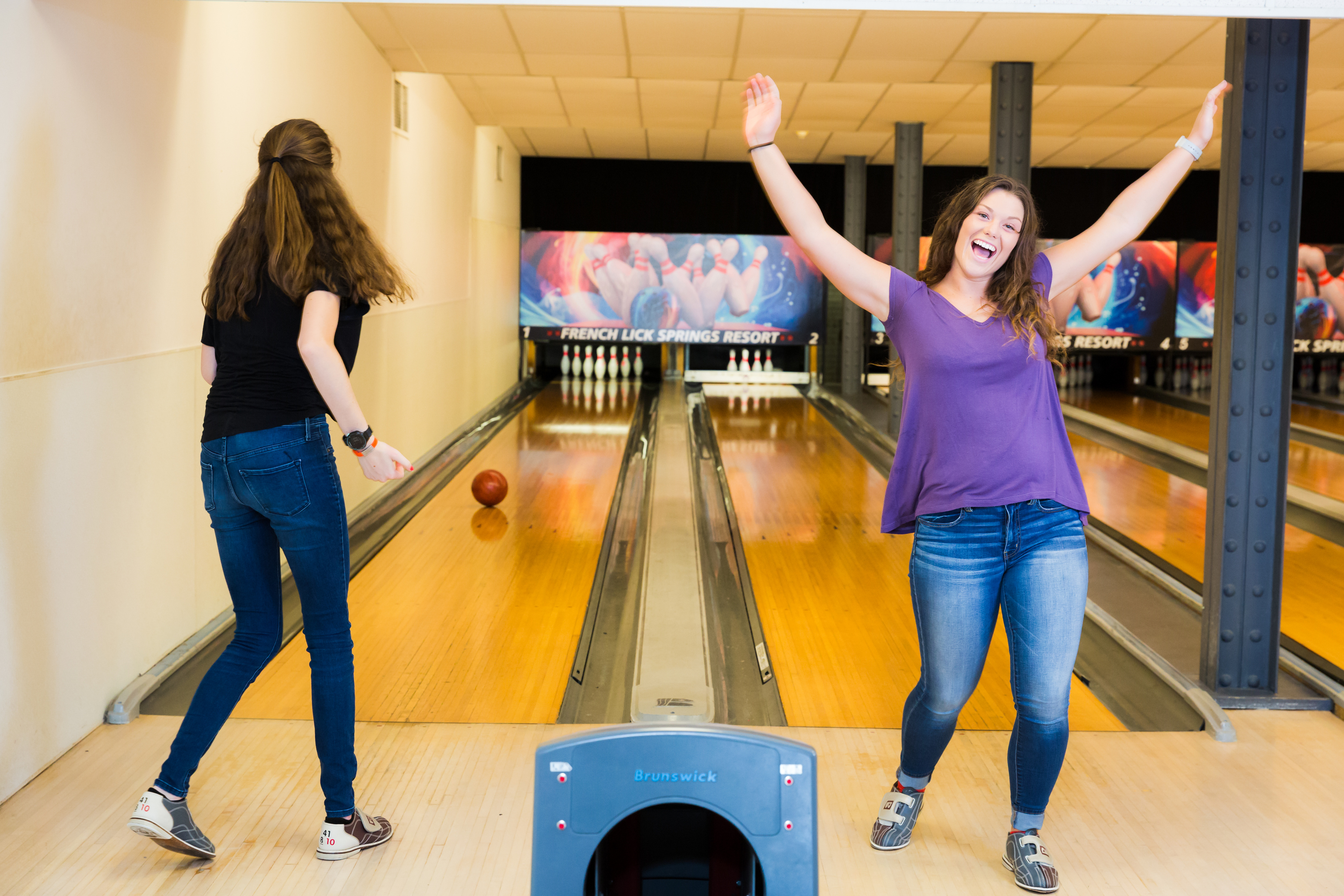 two women standing in a bowling alley