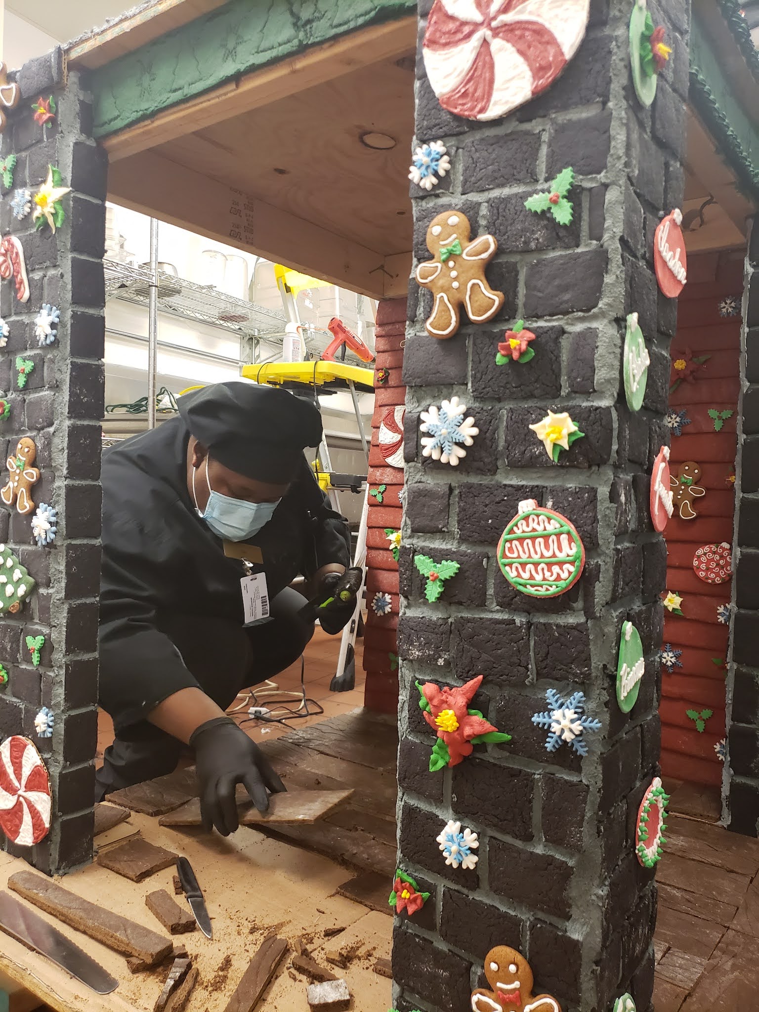 a person in a black coat and black hat working on a brick structure