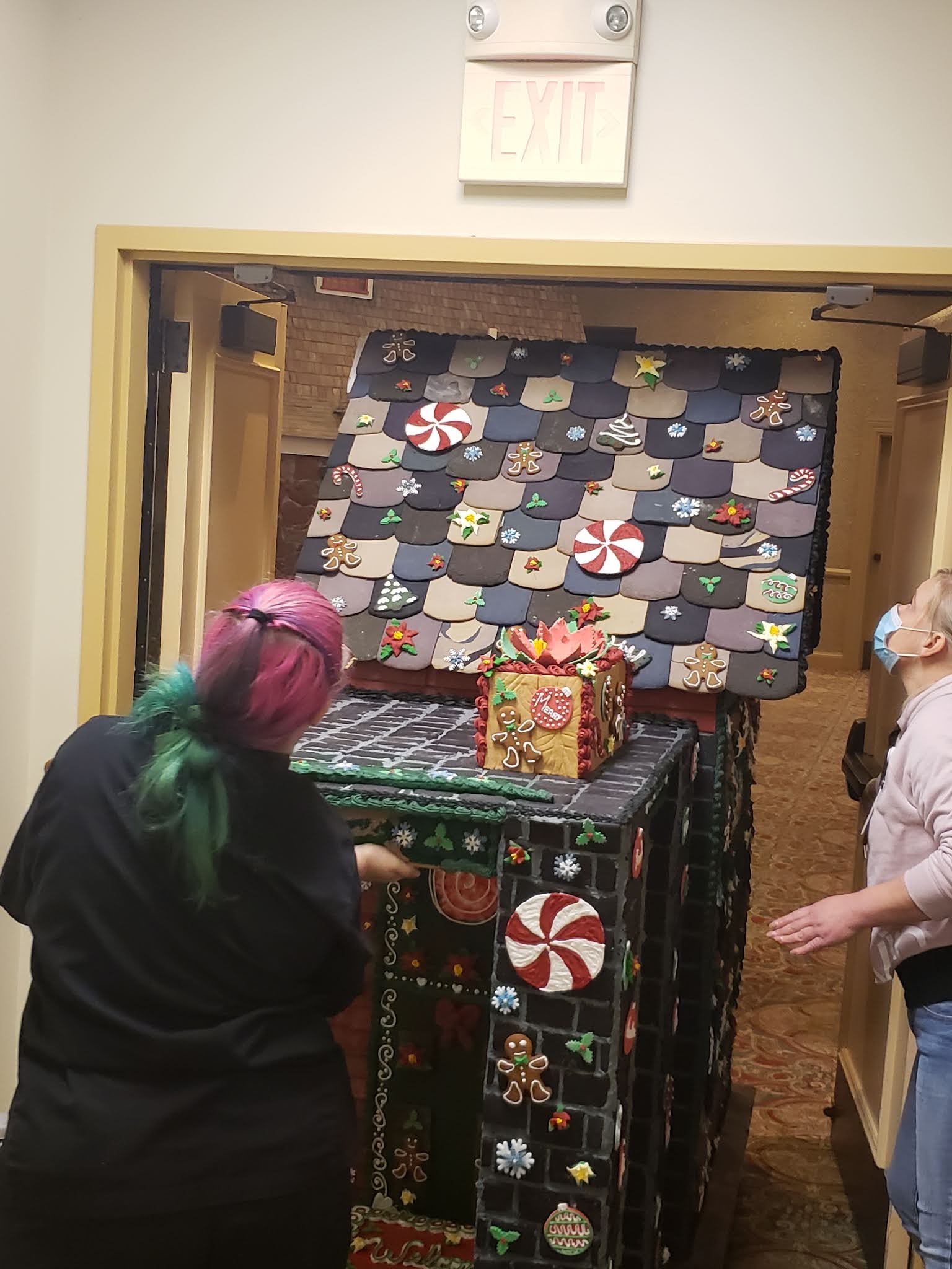 a group of women standing in front of a gingerbread house