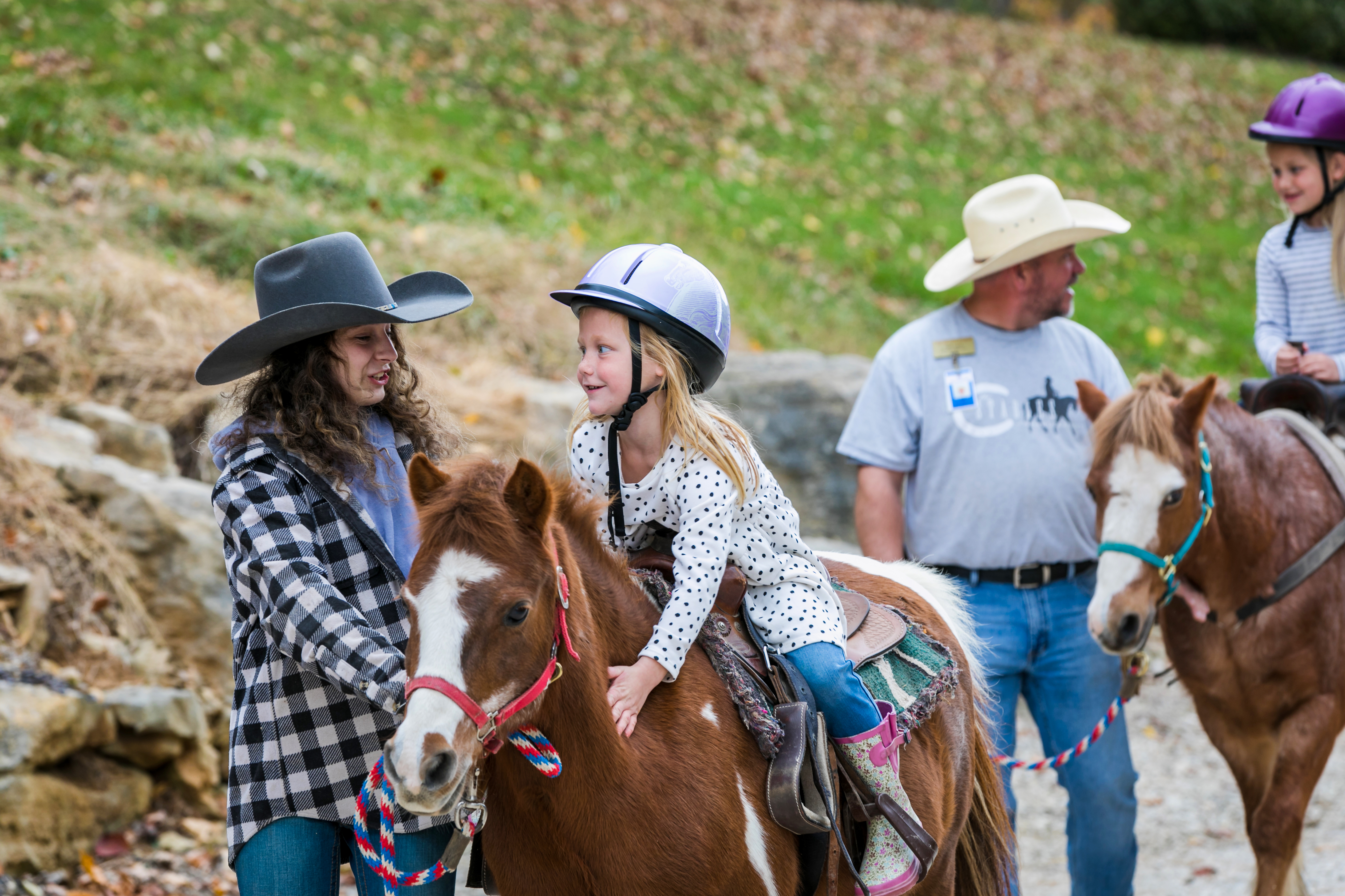 a girl riding a horse with people in cowboy hats