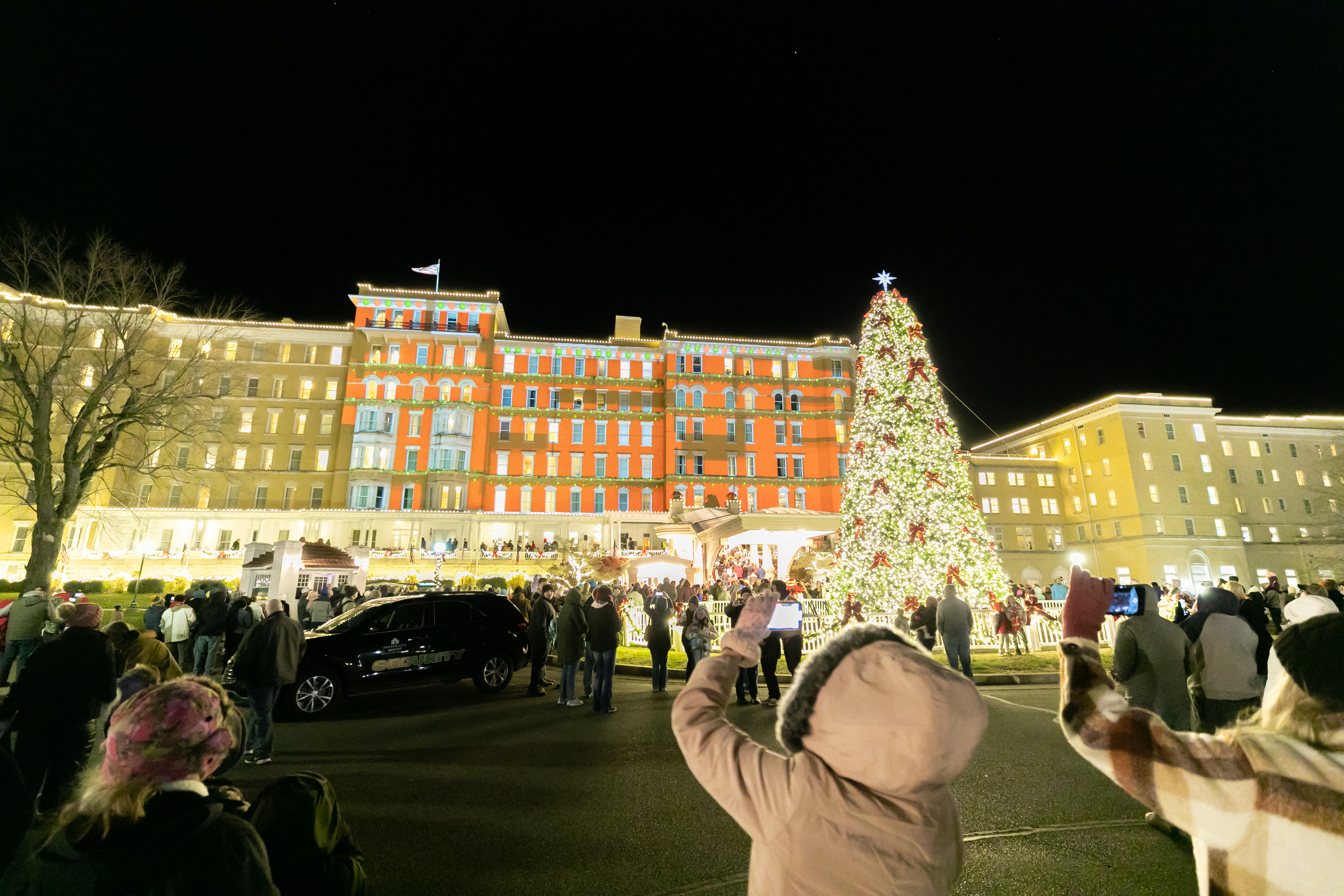 a group of people standing in front of a large building with a christmas tree