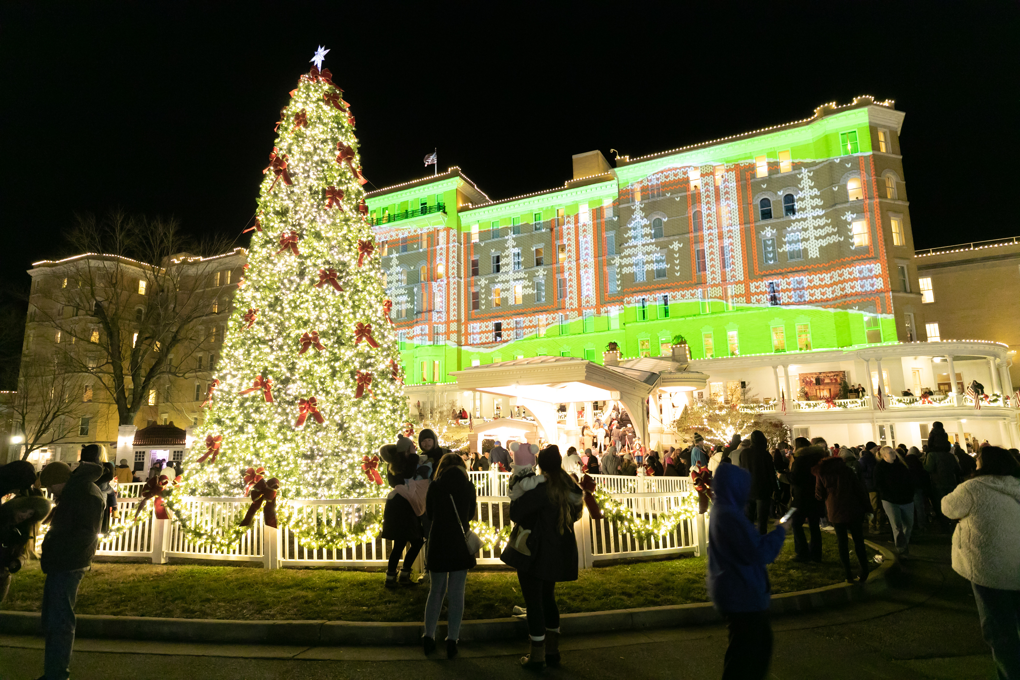 a large building with a large christmas tree and people in front