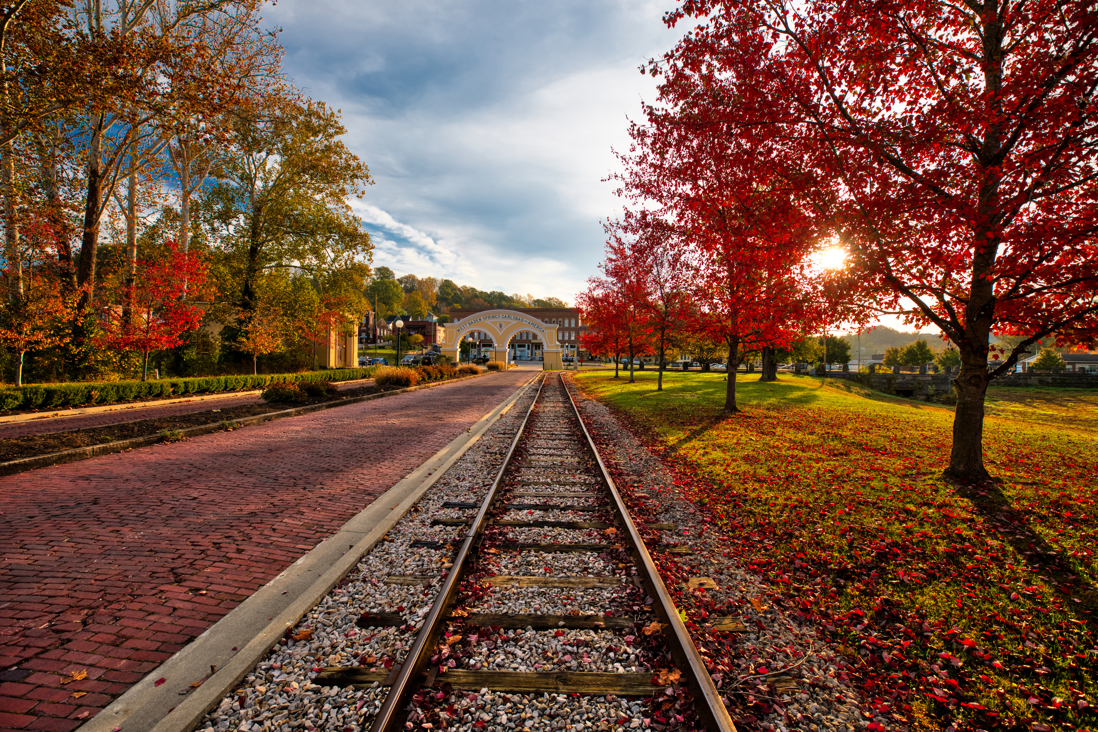 train tracks with red leaves on the ground