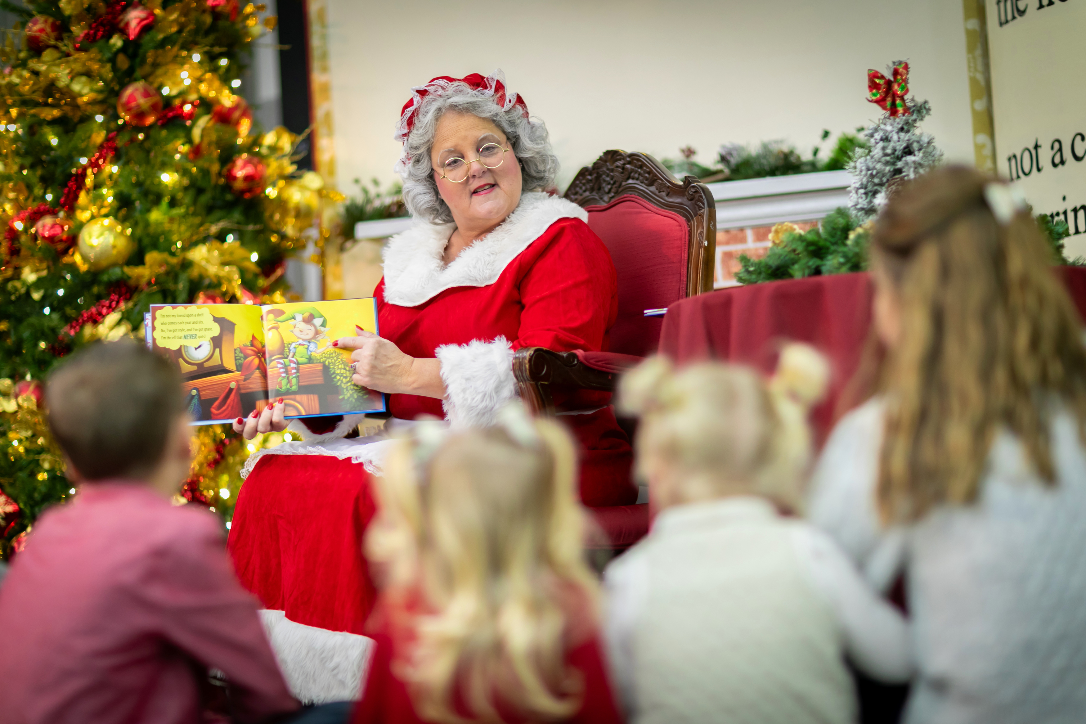 a woman in a red and white garment reading a book to children