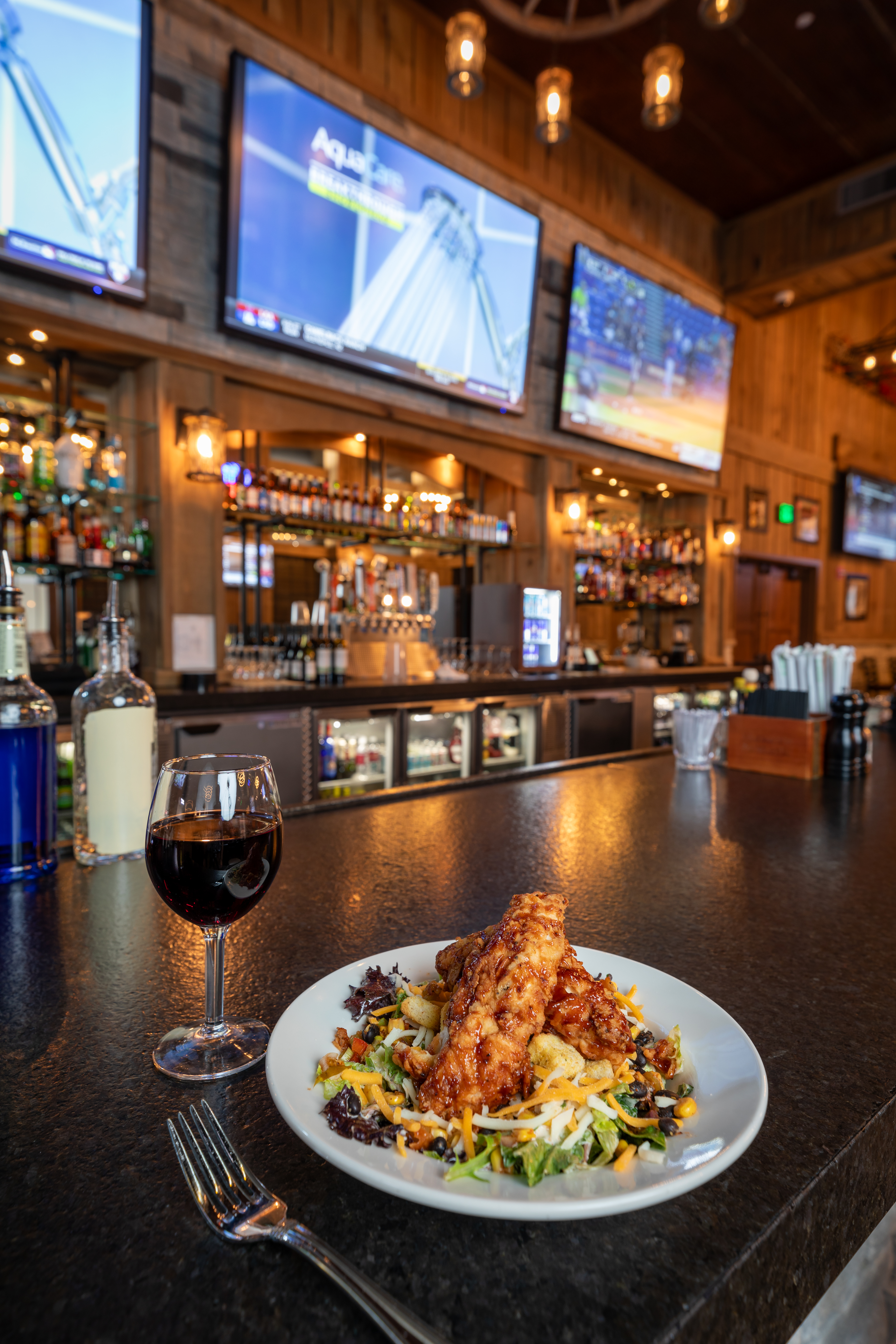 a plate of food and a glass of wine on a bar counter