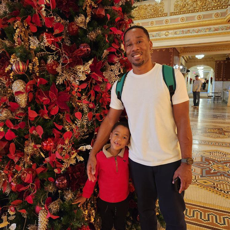 a man and child standing next to a christmas tree