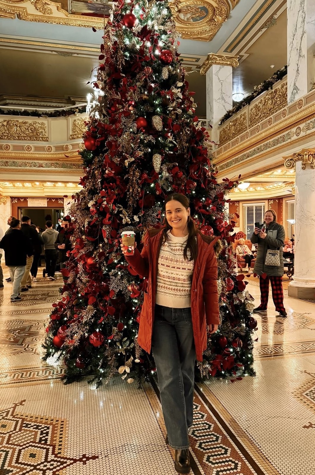 a woman standing in front of a christmas tree