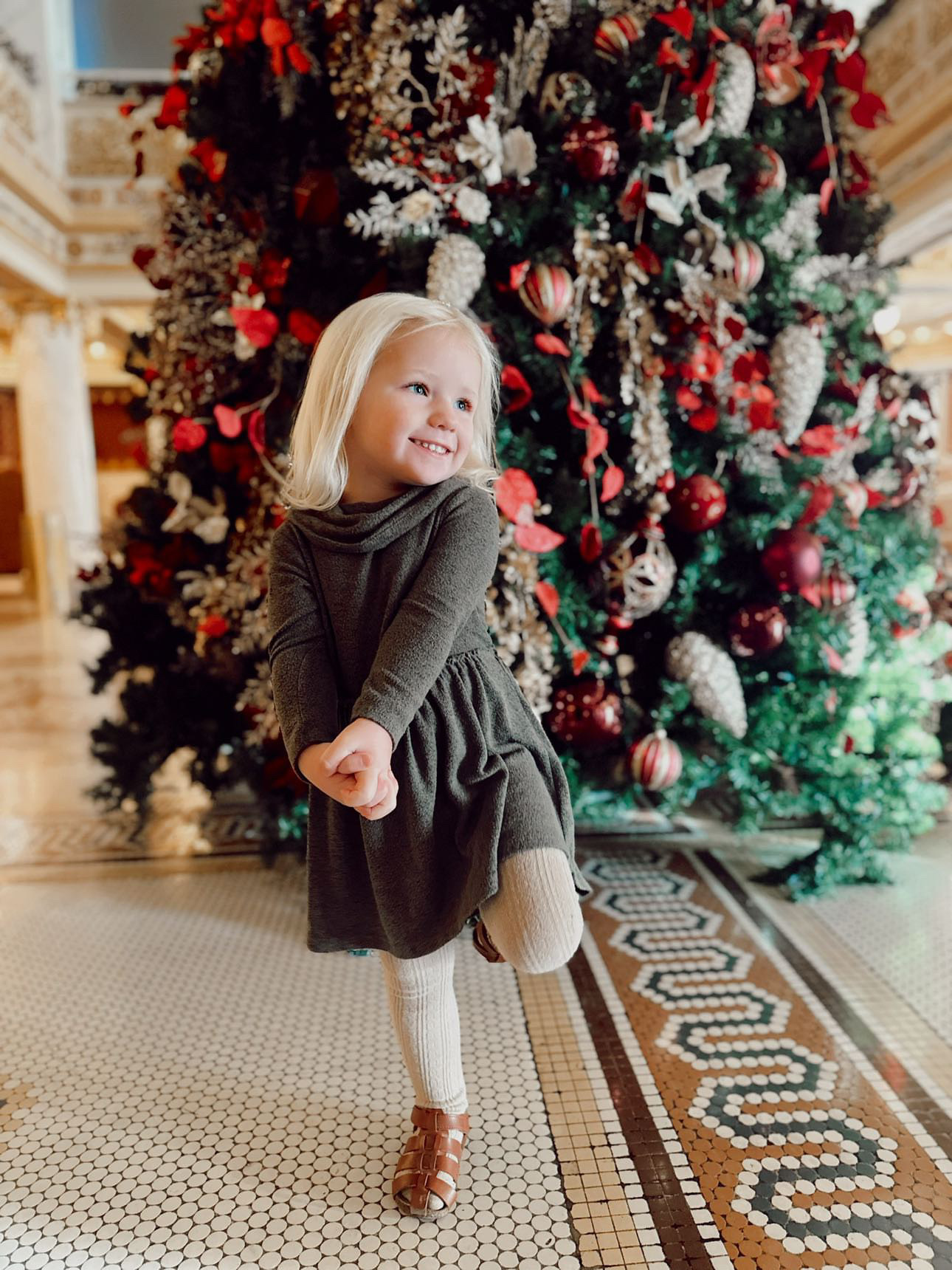 a girl standing in front of a christmas tree