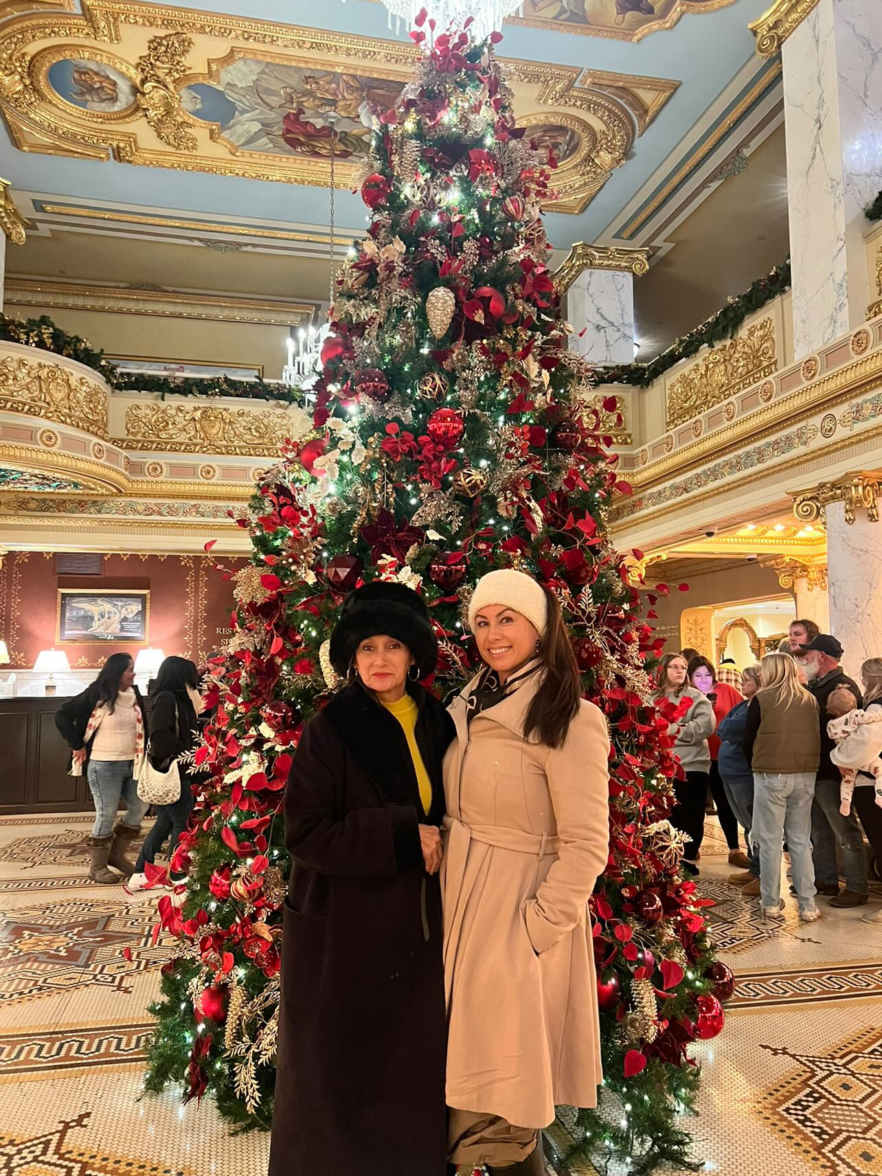 two women standing in front of a christmas tree