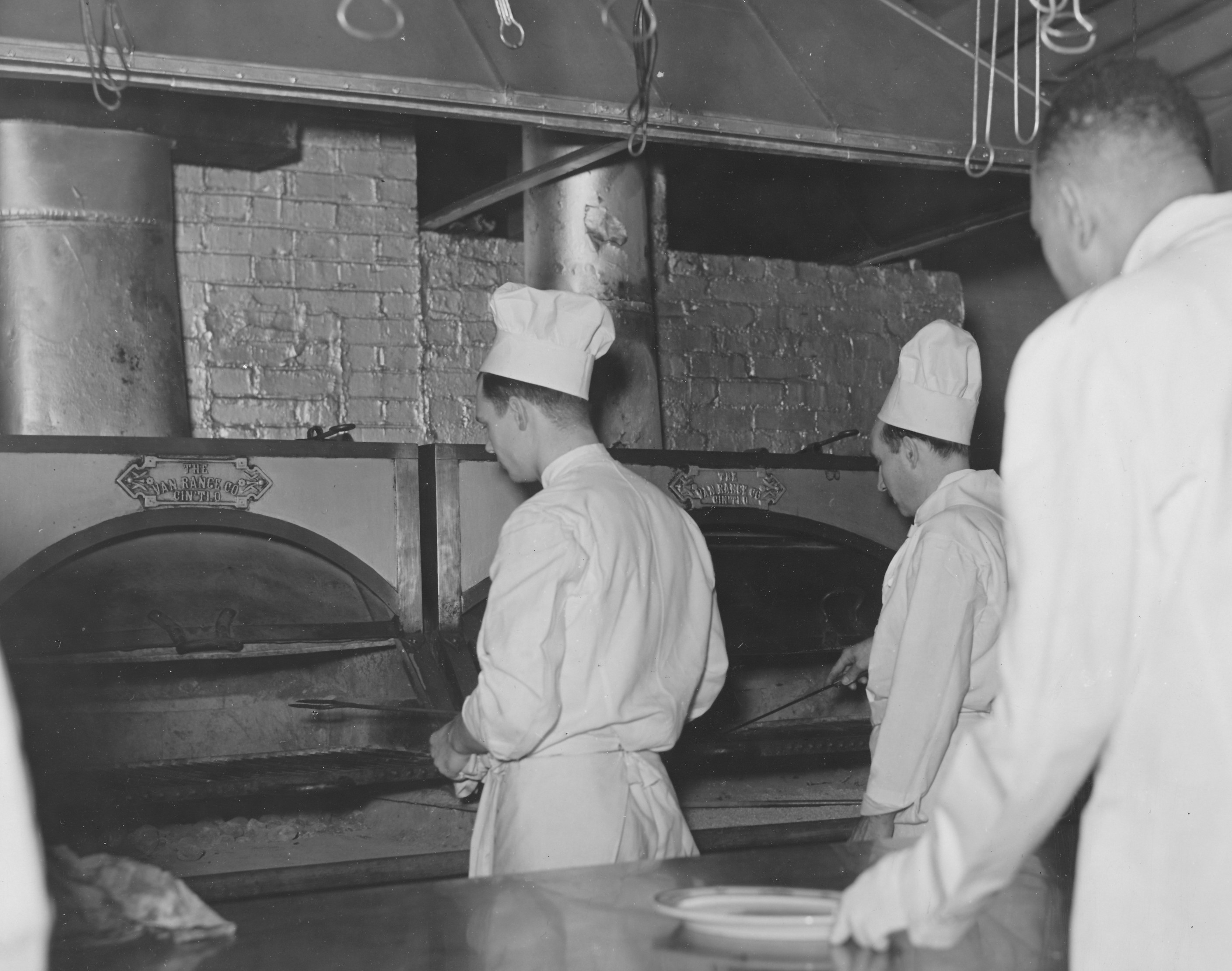 a group of men in chefs uniforms cooking in a kitchen