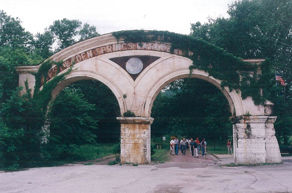 a group of people walking under a stone arch