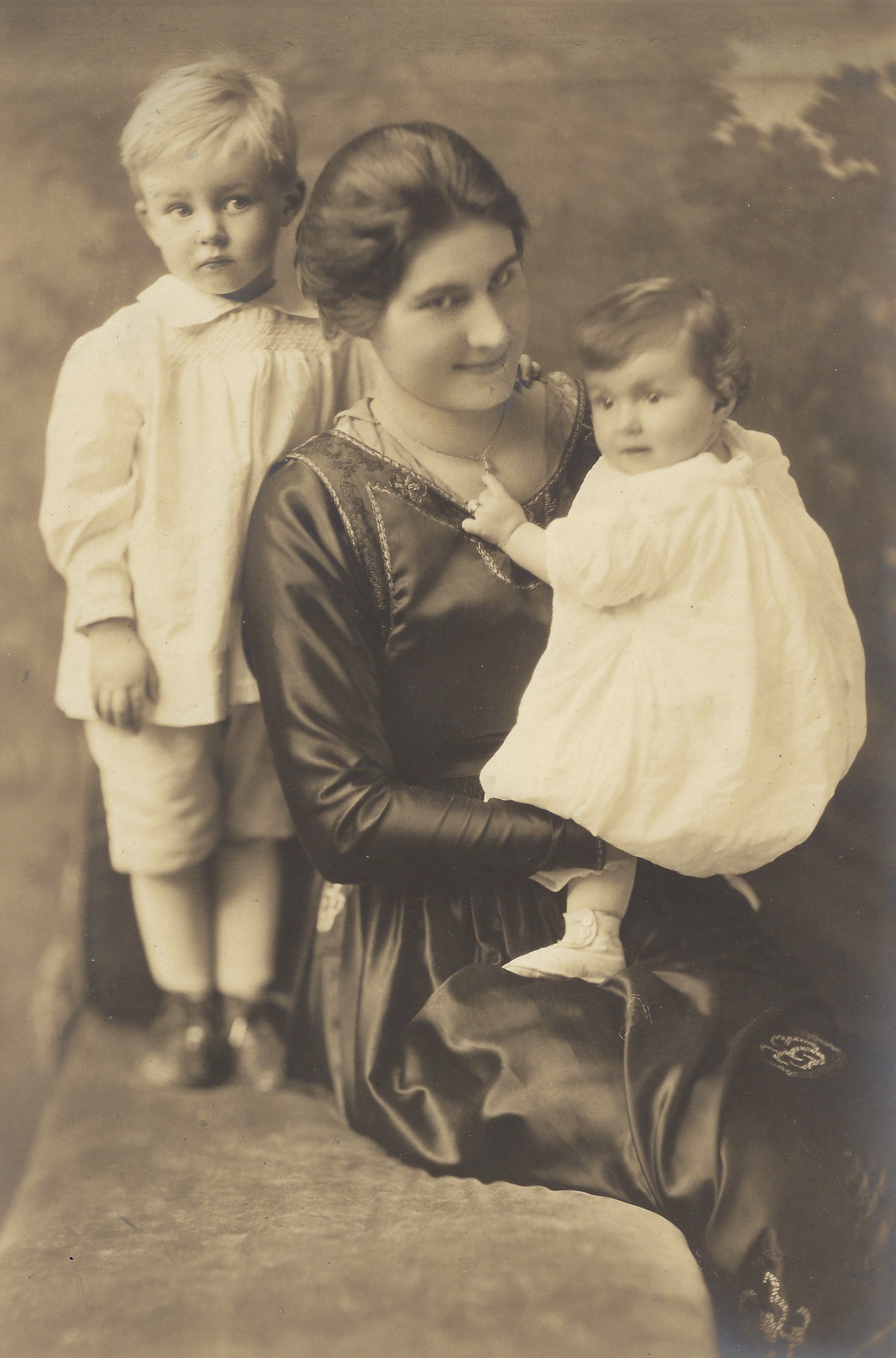 a woman holding a baby and a child standing next to a woman