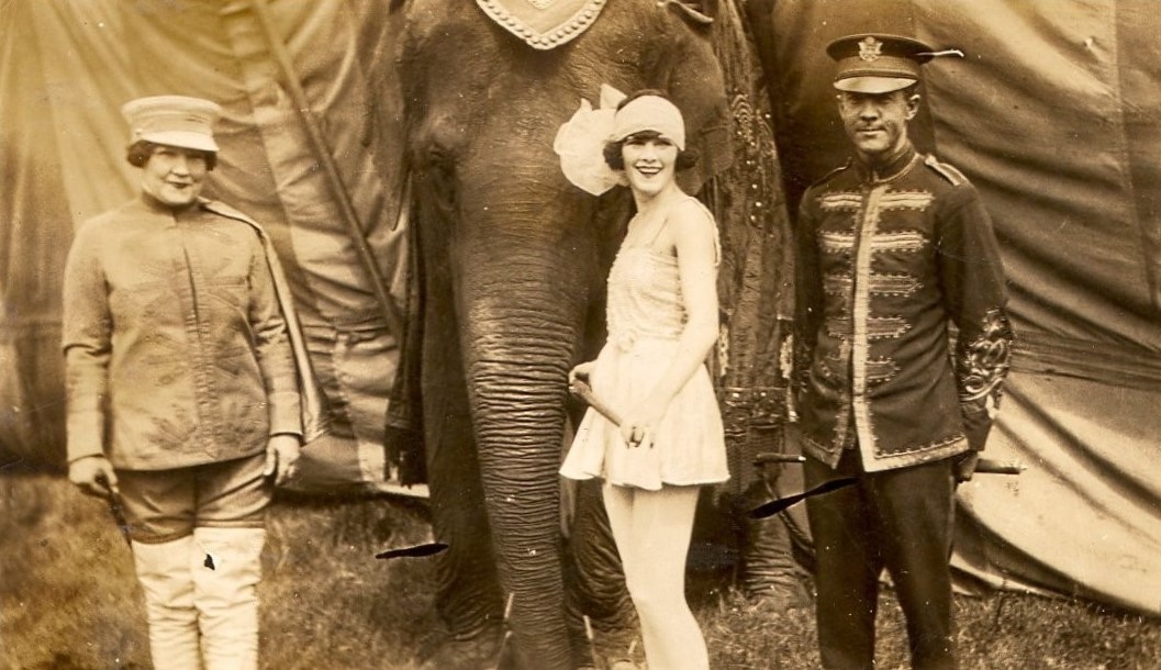 a woman standing next to an elephant