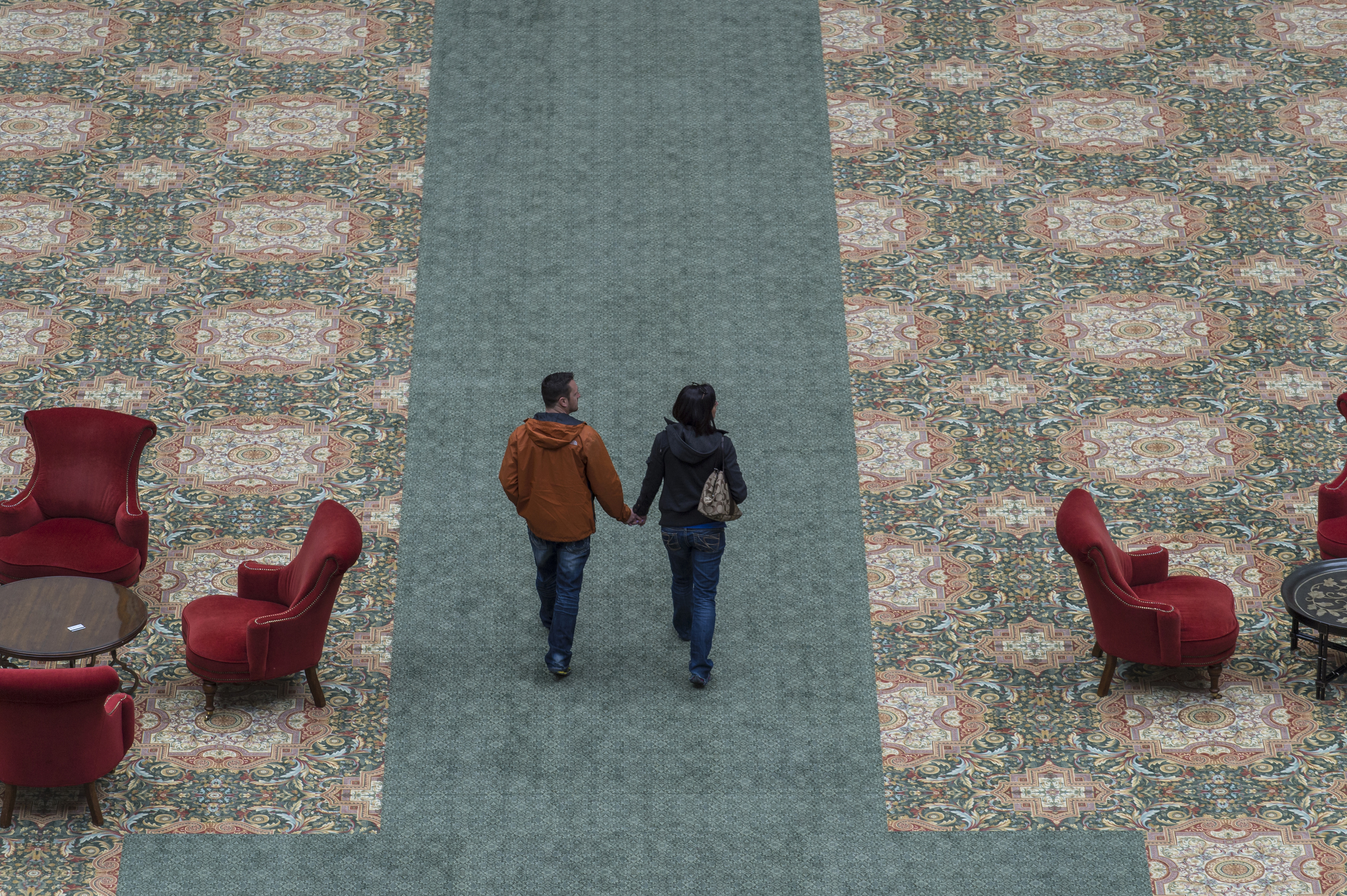 a man and woman holding hands walking on carpet