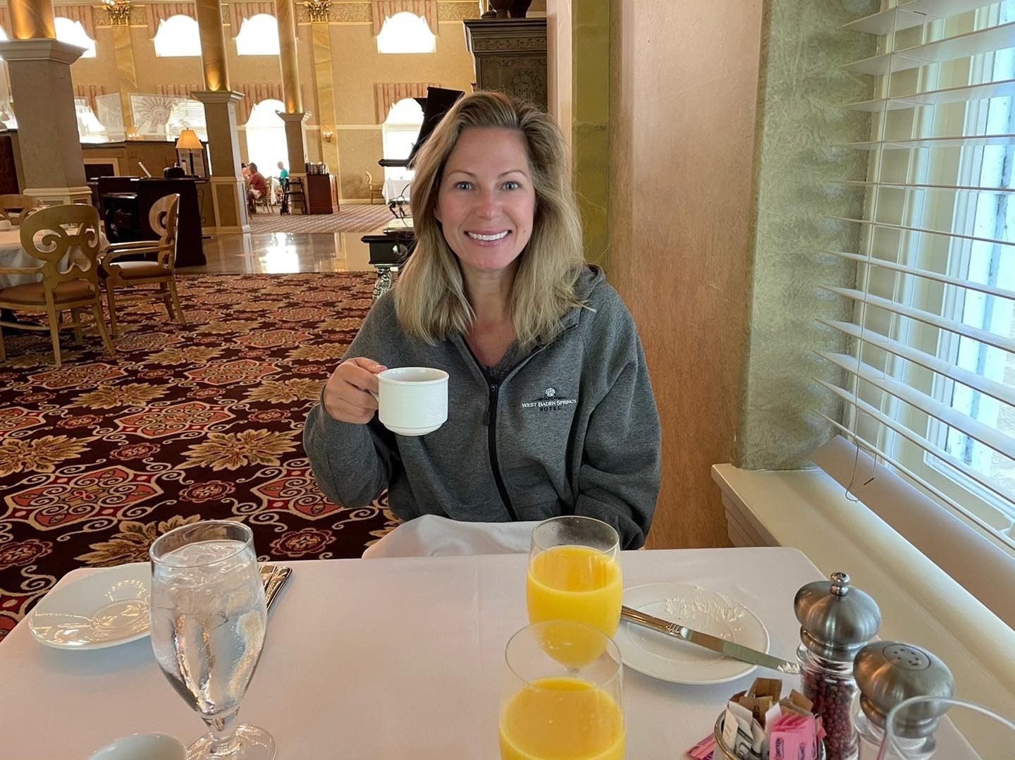 a woman sitting at a table with a cup of coffee