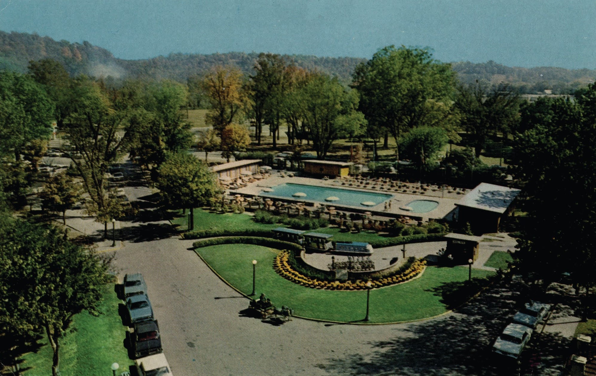 a swimming pool and a park with cars and trees