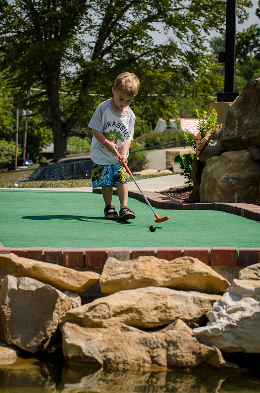 a boy playing mini golf