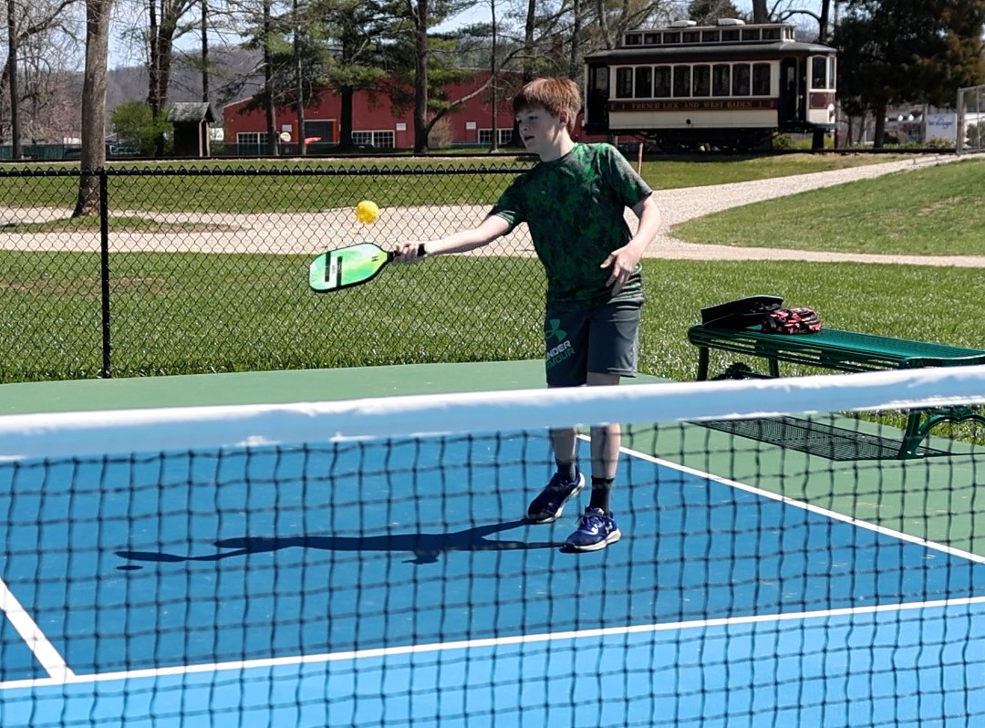 a boy playing tennis on a tennis court