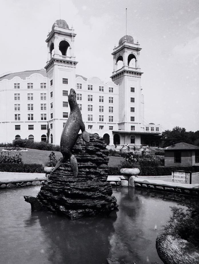 a statue of a seal in a pond with a building in the background