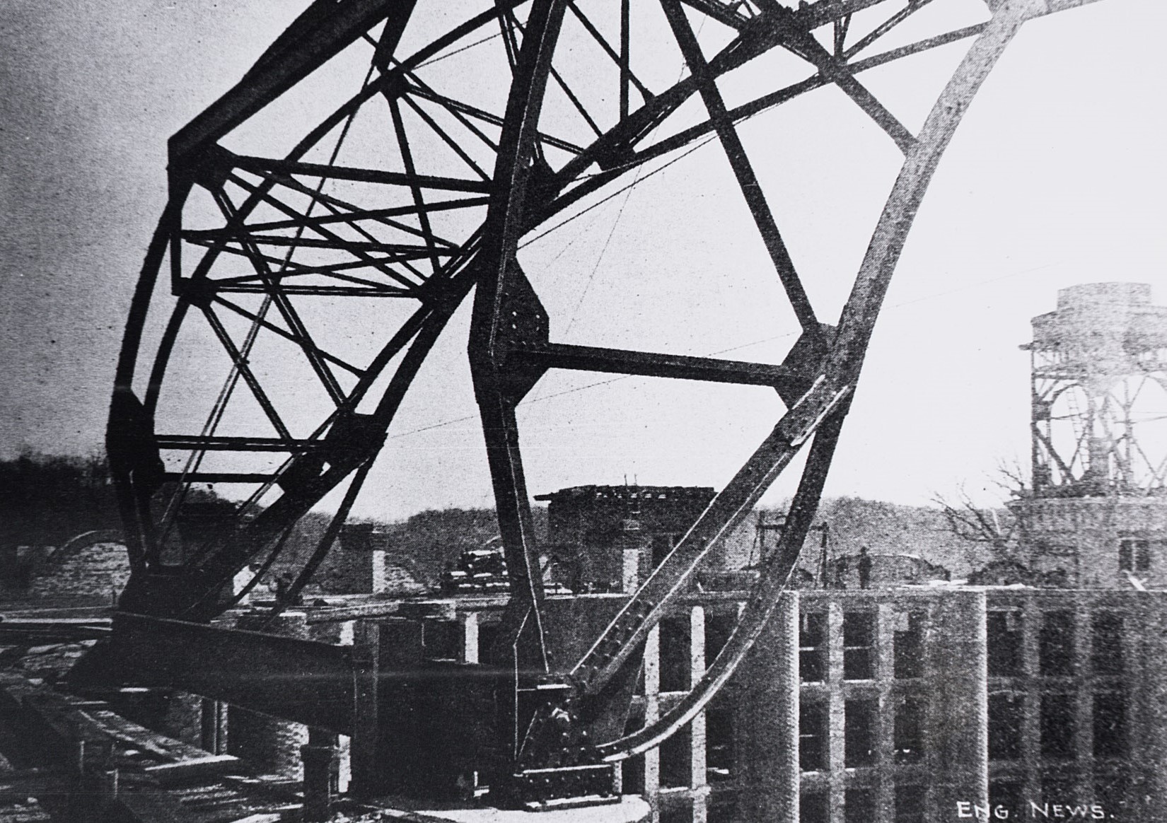 a large metal structure with a building in the background